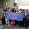 Attendees hold a board that reads 'Leadership... Inspire, Empower, Influence'